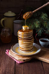 Ein Stapel leckerer Pfannkuchen mit Butter und Honig auf einem Holztisch. - ADSF05281