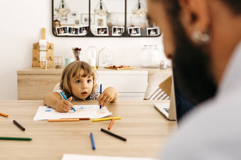 Nettes Mädchen, das seinen Vater beim Malen auf Papier im Esszimmer ansieht - JRFF04589