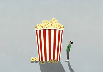 Teenager, der auf einen großen Popcornbecher im Kino schaut - FSIF04720