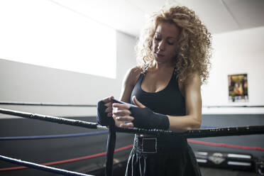 Fitness-Frau in Sportkleidung wickelt Boxbandage - ADSF05298