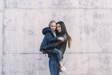 Girl holding up young sister while looking at camera - ADSF05351