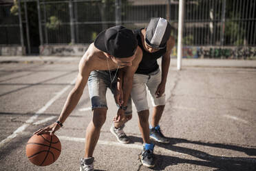 Junger Afro-Junge spielt mit seinem Bruder Basketball auf dem Platz in seiner Nachbarschaft - ADSF05370