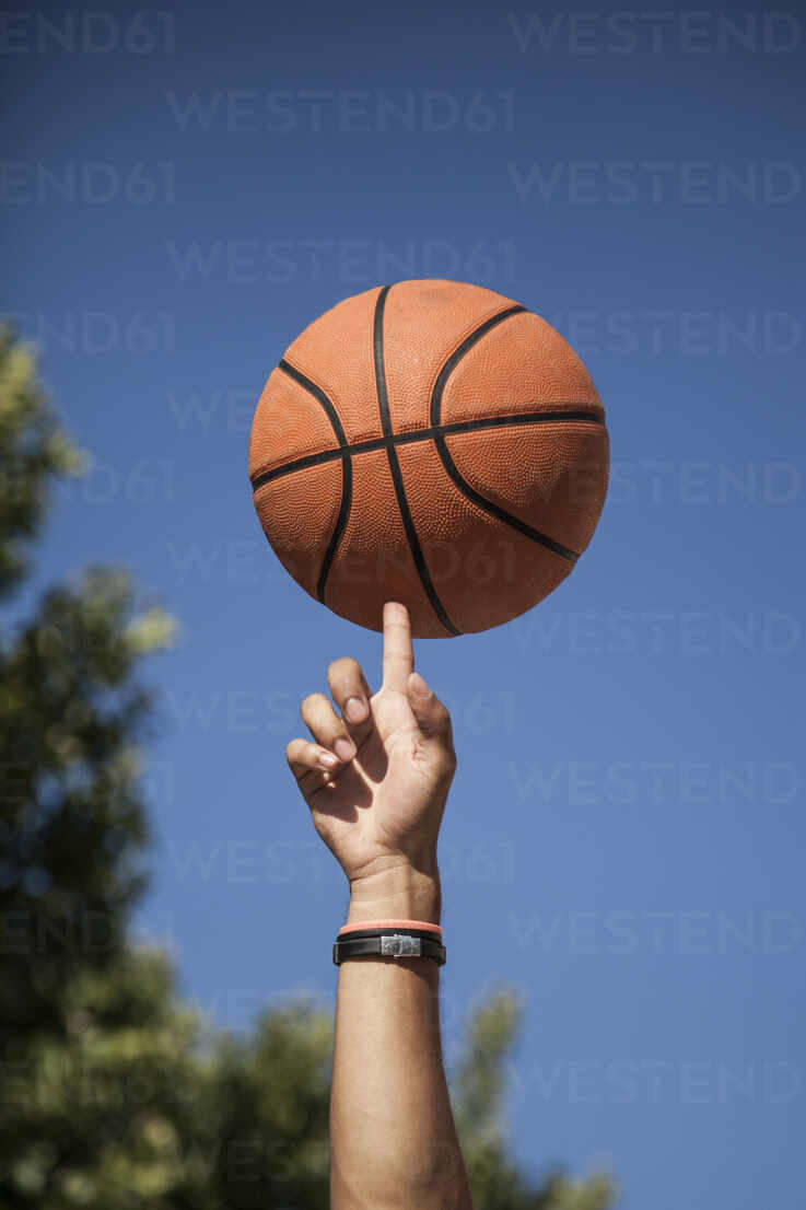 Hand spinning the basketball on a finger with blue sky background stock  photo
