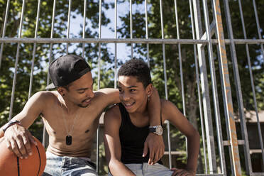 Junge Afro-Brüder spielen Basketball auf dem Platz in ihrer Nachbarschaft und umarmen sich lächelnd - ADSF05393