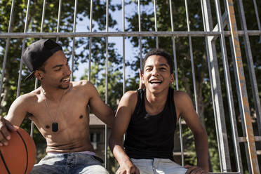 Junge Afro-Brüder spielen Basketball auf dem Platz in ihrer Nachbarschaft und umarmen sich lächelnd - ADSF05394