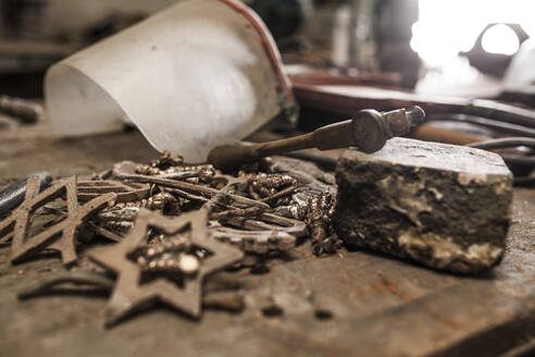 Iron fittings anvil hammer and mask on blacksmith table - ADSF05448