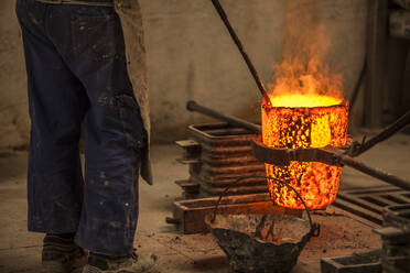 Schnittansicht eines Mannes in Arbeitskleidung, der in einem Ofen mit brennendem Feuer steht und Kohlen verhindert - ADSF05451