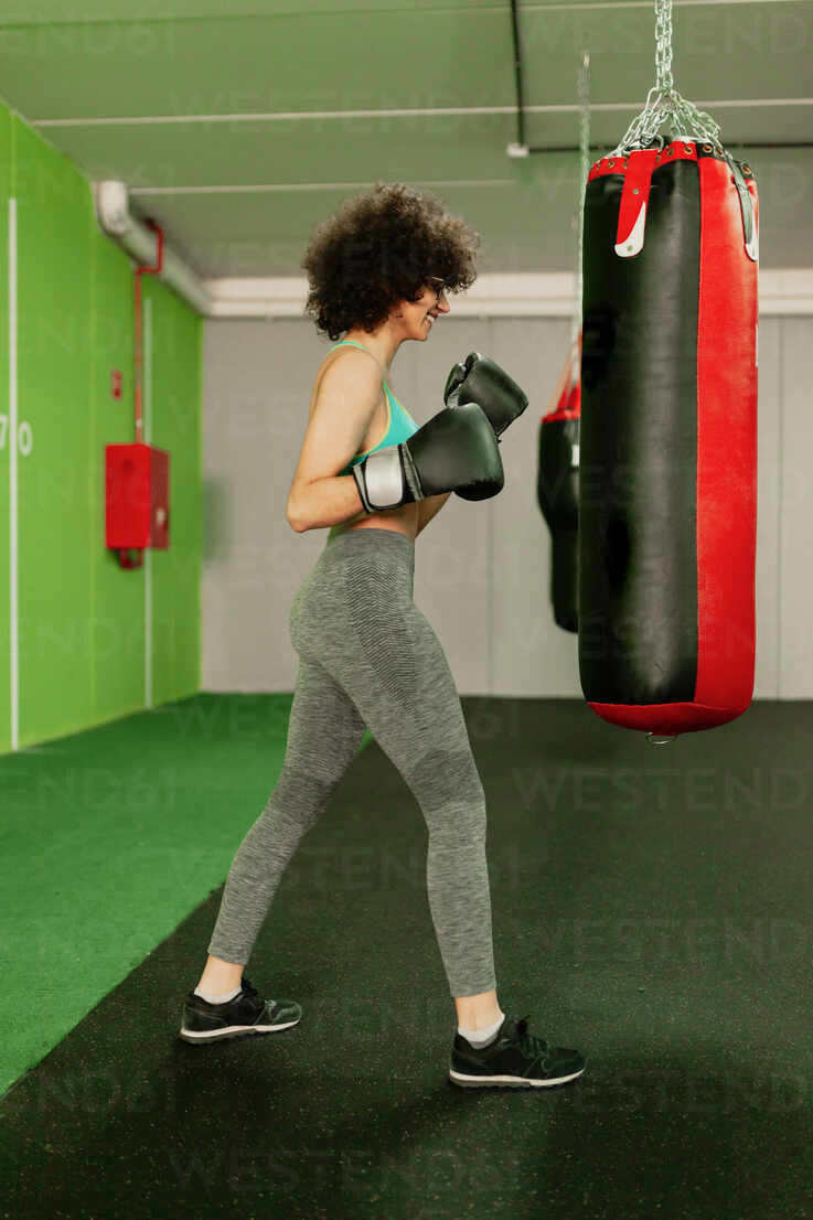 Woman in Boxing Gloves With Sports Bra Posing Boxing Style in Front of  Punching Bag · Free Stock Photo