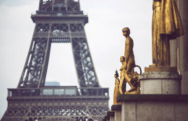 Nahaufnahme von goldbedeckten Statuen von Menschen auf dem Hintergrund des Eiffelturms in Paris - ADSF05721