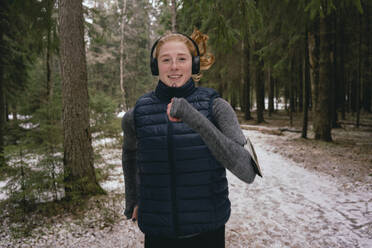 Porträt einer selbstbewussten Frau, die in einem verschneiten Wald läuft - FSIF05077