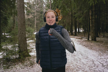 Portrait confident woman running in snowy woods - FSIF05077