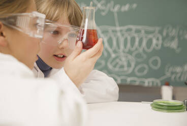 Junior high school students examining beaker of liquid in science class - FSIF05101