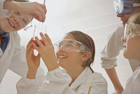 Fröhliche Gymnasiasten mit Schutzbrillen bei einem wissenschaftlichen Experiment - FSIF05102