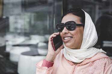 Nette marokkanische Frau mit Hidschab und typisch arabischer Kleidung beim Telefonieren - ADSF05894