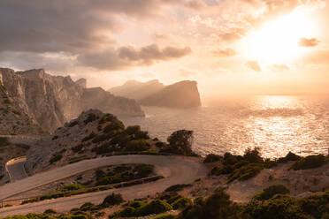 Kurvenreiche Straße und Steilküste auf Mallorca mit rötlichen Tönen des Sonnenuntergangs - CAVF87399