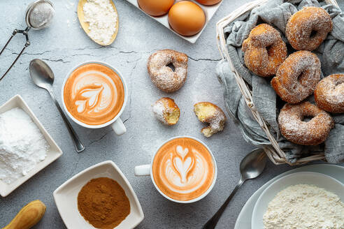 Kaffee mit Latte Art und kleinen Krapfen von Wein mit Zucker und Zimt und Zutaten. Donuts Dessert - CAVF87414