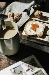 Leckeres Toastbrot mit Butter und Marmelade, daneben eine Kaffeetasse und Walnüsse - CAVF87416