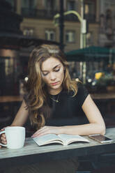 Junge Frau liest ein Buch in einem Cafe - ADSF06000