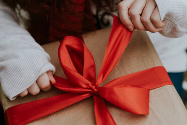 Abgeschnittene Aufnahme eines Mädchens, das ein Paket mit einem Weihnachtsgeschenk aufmacht. - ADSF06070