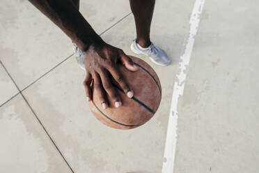 Crop männliche Hand mit Basketball beim Spielen auf dem Boden. - ADSF06078