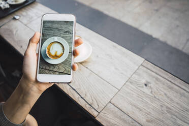 Von oben, aus der Hand einer nicht erkennbaren Person, die eine Kaffeetasse auf dem Tisch fotografiert. - ADSF06104