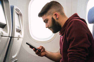 Bärtiger Mann benutzt Smartphone im Flugzeug - ADSF06112