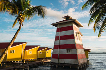 Tropical seashore with small wooden lighthouse on pier with yellow houses in row, Panama - ADSF06124