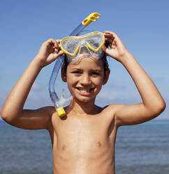 Lächelnder Junge nimmt Schnorchel und Schwimmbrille ab - CAIF28386