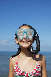 Happy girl wearing snorkel and goggles on beach - CAIF28390