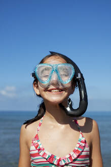 Glückliches Mädchen mit Schnorchel und Schwimmbrille am Strand - CAIF28390