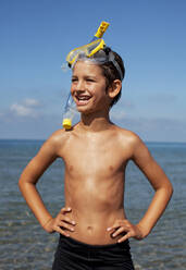 Smiling boy wearing snorkel and goggles on beach - CAIF28394