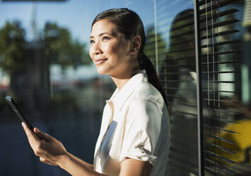 Smiling businesswoman using digital tablet outdoors - CAIF28419