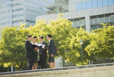 Business people discussing paperwork outdoors - CAIF28430