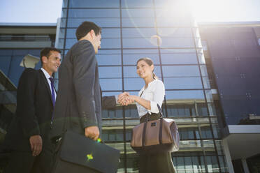 Business people shaking hands under highrise - CAIF28445