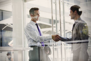 Businessmen shaking hands in office - CAIF28462