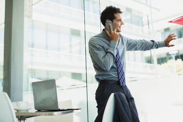 Businessman talking on cell phone at window - CAIF28470