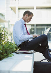 Businessman working on laptop outdoors - CAIF28488