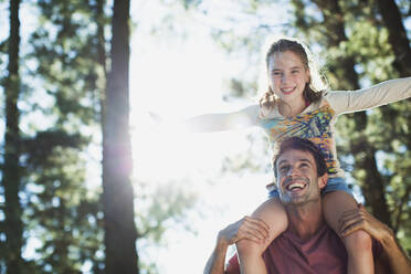 Happy daughter on fathers shoulders in woods - CAIF28493