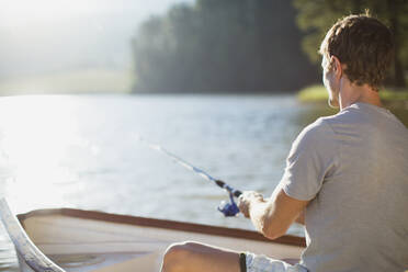 Mann fischt in Ruderboot auf ruhigem See - CAIF28496