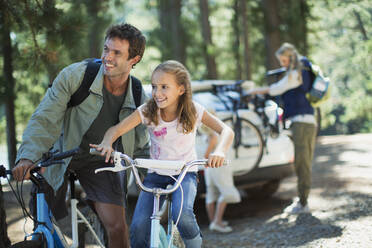 Vater und Tochter auf Fahrrädern im Wald - CAIF28505