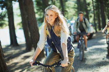 Lächelnde Frau beim Fahrradfahren im Wald - CAIF28507