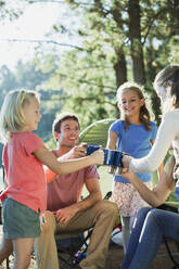 Familie stößt mit Tassen auf dem Campingplatz im Wald an - CAIF28518