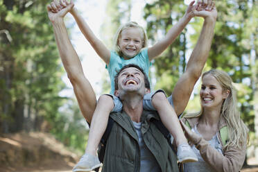 Father carrying daughter on shoulders in woods - CAIF28531