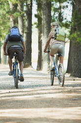 Pärchen beim Mountainbiking mit Rucksäcken im Wald - CAIF28534