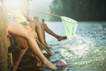 Family on dock with fishing nets dipping feet in lake - CAIF28537