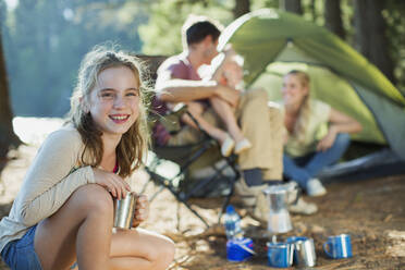 Lächelndes Mädchen auf dem Campingplatz mit Familie im Wald - CAIF28540