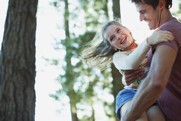 Father spinning daughter in woods - CAIF28542