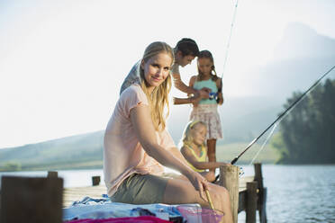 Smiling woman with family fishing on dock over lake stock photo