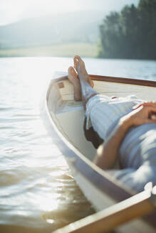 Serene man laying rowboat on calm lake - CAIF28550