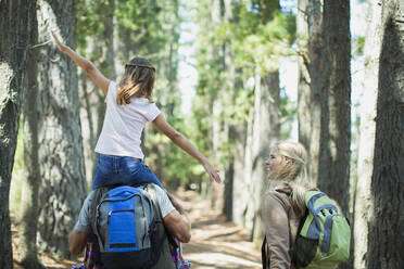 Father carrying daughter on shoulders in woods - CAIF28552